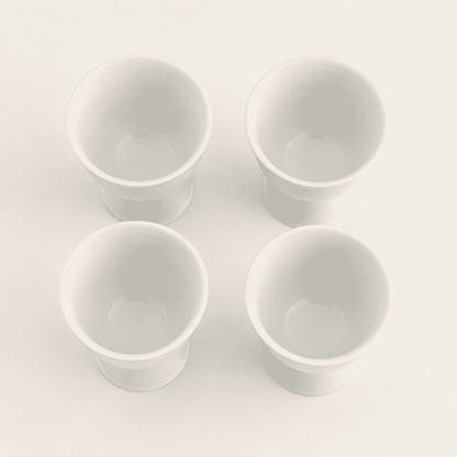 Top-down view of four white porcelain footed cups showing openings