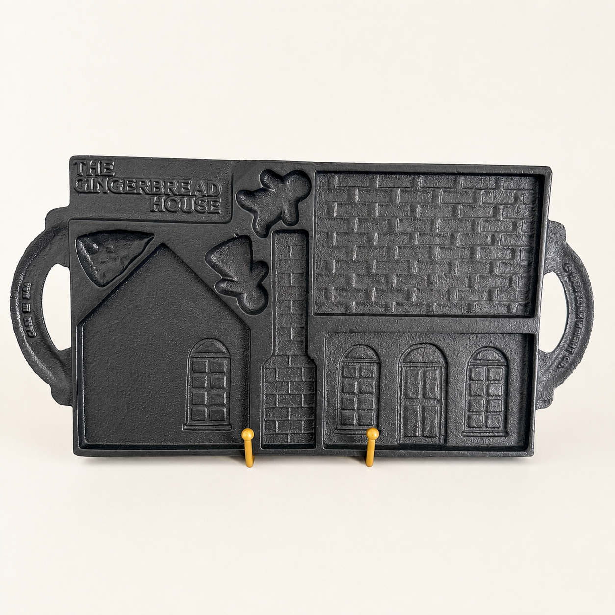 Angled view of the cast iron gingerbread house mold on a stand
